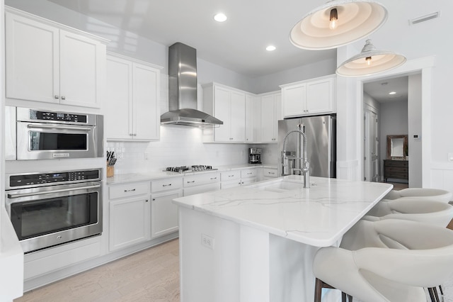 kitchen featuring stainless steel appliances, visible vents, backsplash, a sink, and wall chimney exhaust hood