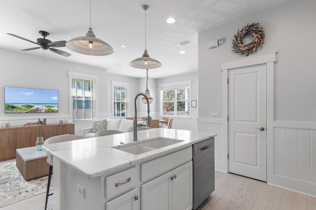 kitchen featuring open floor plan, a wainscoted wall, dishwasher, and a sink