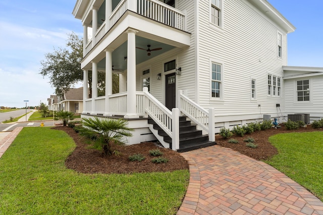 exterior space with a lawn, ceiling fan, central air condition unit, a balcony, and a porch