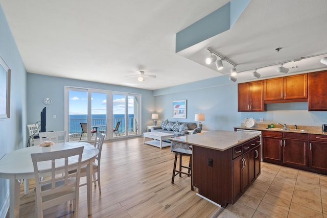 kitchen with rail lighting, a breakfast bar, ceiling fan, sink, and a kitchen island