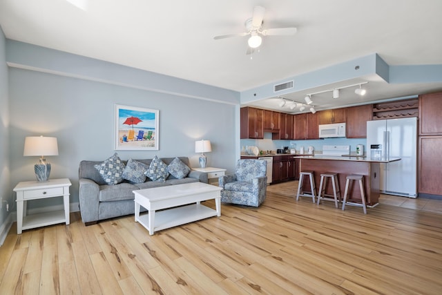 living room with ceiling fan, light hardwood / wood-style floors, and rail lighting