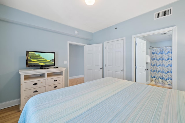 bedroom featuring connected bathroom and light hardwood / wood-style floors