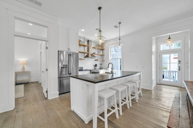 kitchen with white cabinets, island exhaust hood, light hardwood / wood-style flooring, a breakfast bar, and appliances with stainless steel finishes