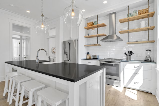 kitchen featuring wall chimney exhaust hood, decorative light fixtures, tasteful backsplash, white cabinetry, and appliances with stainless steel finishes