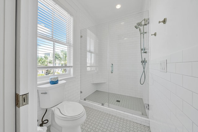 bathroom featuring tile walls, a shower with door, tile patterned flooring, and toilet