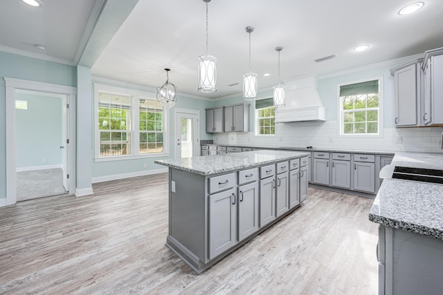 kitchen featuring custom exhaust hood, decorative backsplash, hanging light fixtures, a kitchen island, and gray cabinetry