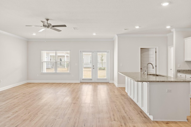 kitchen featuring sink, white cabinets, ceiling fan, a kitchen island with sink, and crown molding