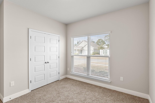 unfurnished bedroom featuring light colored carpet and a closet