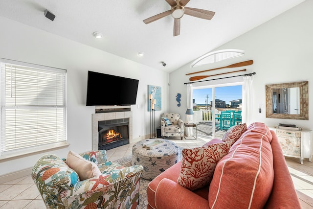 living room featuring vaulted ceiling, a tiled fireplace, ceiling fan, and light tile patterned floors