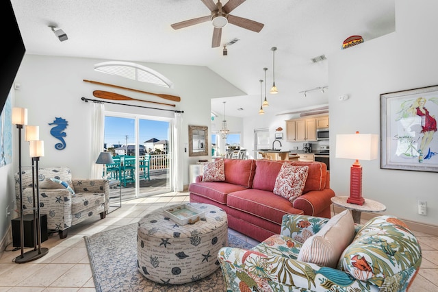 tiled living room featuring a textured ceiling, ceiling fan, and vaulted ceiling