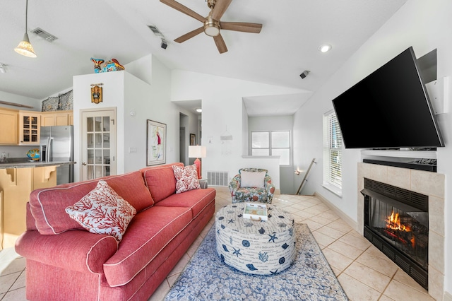 living room with light tile patterned floors, a tile fireplace, ceiling fan, and vaulted ceiling