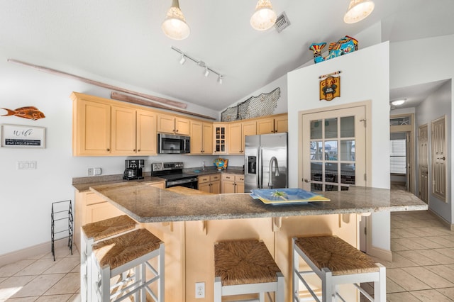 kitchen featuring a breakfast bar area, appliances with stainless steel finishes, lofted ceiling, light brown cabinets, and light tile patterned flooring