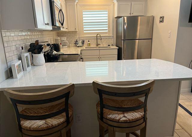 kitchen featuring light tile patterned floors, appliances with stainless steel finishes, a breakfast bar, and sink