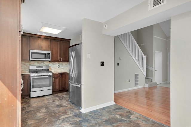 kitchen with appliances with stainless steel finishes, tasteful backsplash, and dark brown cabinetry