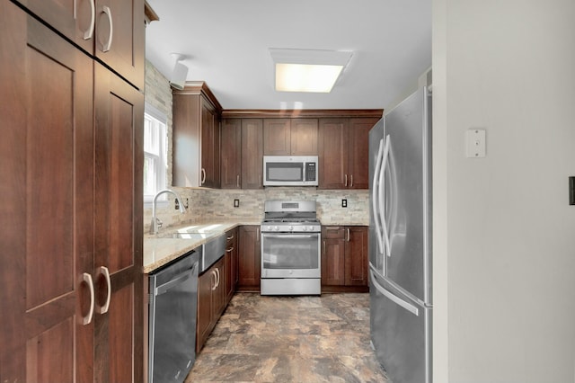 kitchen with sink, backsplash, light stone counters, and appliances with stainless steel finishes