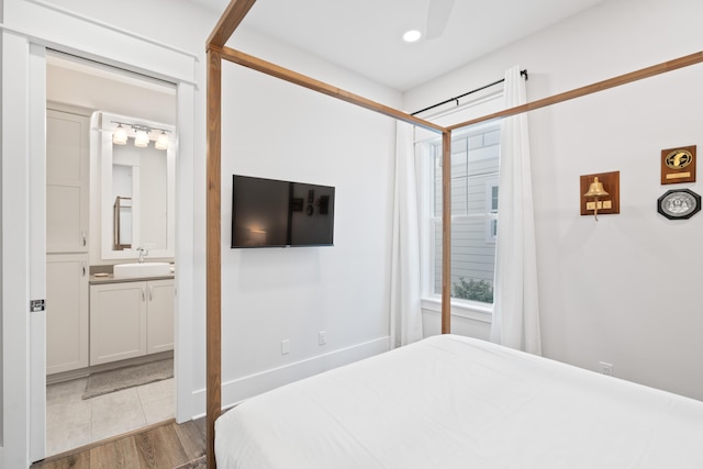 bedroom with sink, ensuite bath, and light hardwood / wood-style floors