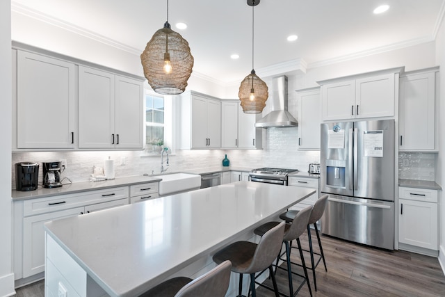 kitchen featuring sink, hanging light fixtures, stainless steel appliances, a center island, and wall chimney exhaust hood