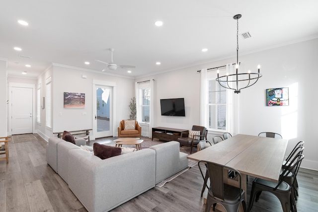 living room with crown molding, ceiling fan with notable chandelier, and light wood-type flooring