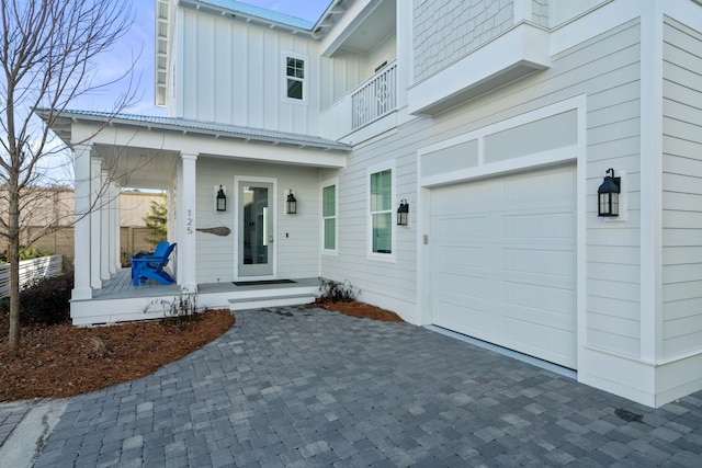 view of exterior entry with a garage and a porch