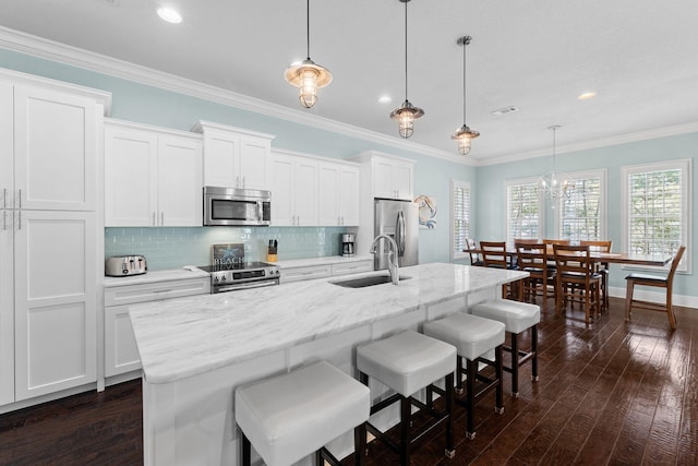 kitchen featuring appliances with stainless steel finishes, an island with sink, white cabinets, and sink