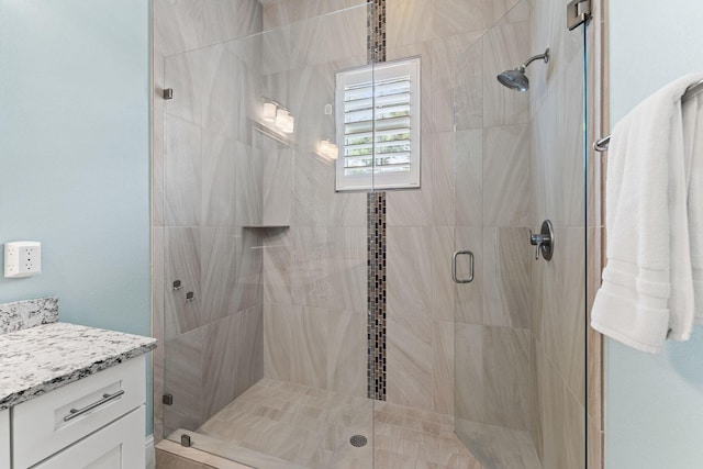 bathroom featuring a shower with shower door and vanity