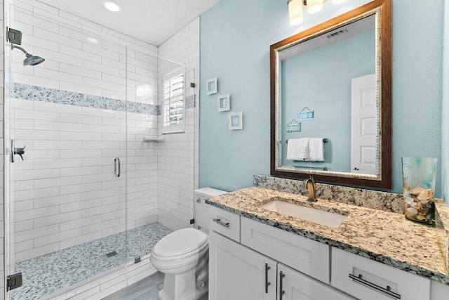 bathroom with a shower with door, vanity, and toilet