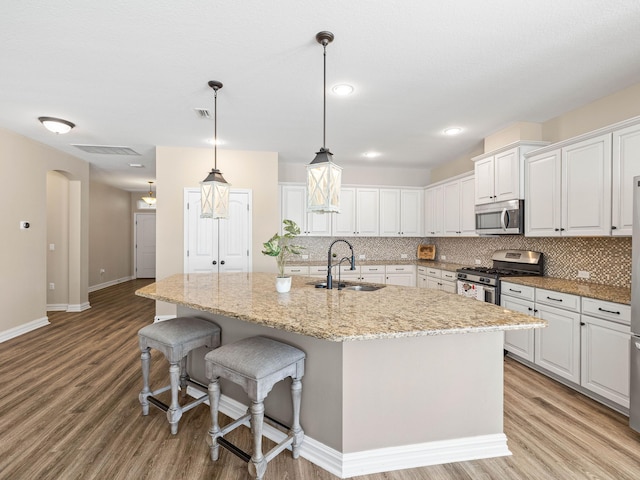 kitchen featuring appliances with stainless steel finishes, an island with sink, white cabinets, and sink