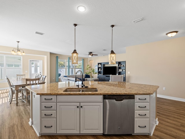 kitchen featuring sink, ceiling fan with notable chandelier, stainless steel dishwasher, and a center island with sink