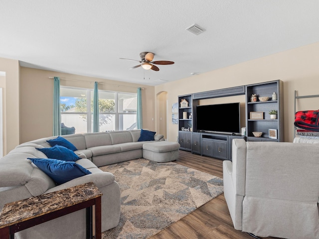 living room with ceiling fan and dark wood-type flooring