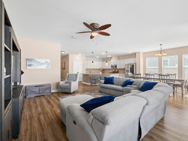 living room featuring ceiling fan with notable chandelier and hardwood / wood-style floors