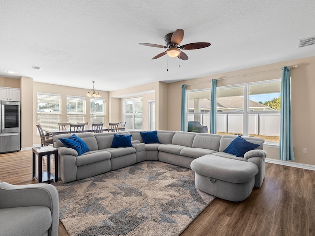 living room featuring a textured ceiling, hardwood / wood-style floors, a wealth of natural light, and ceiling fan with notable chandelier