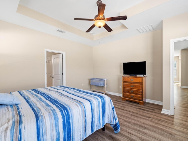 bedroom featuring a raised ceiling, ceiling fan, and wood-type flooring