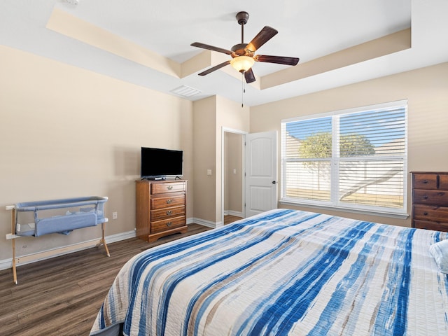 bedroom featuring dark hardwood / wood-style flooring, a raised ceiling, and ceiling fan