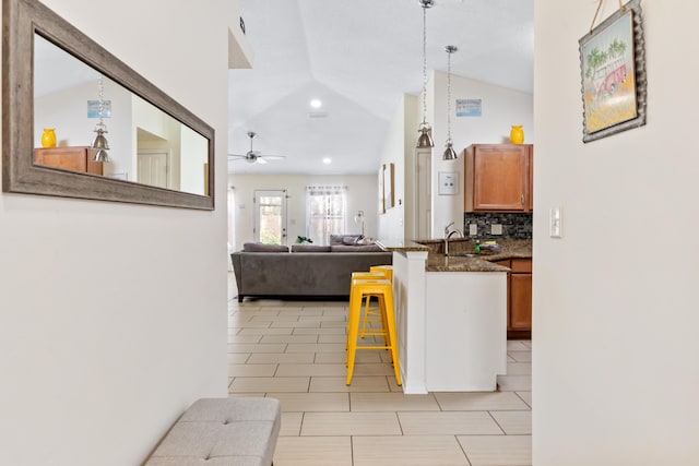 kitchen featuring lofted ceiling, backsplash, sink, ceiling fan, and decorative light fixtures