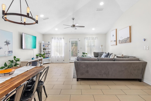 living room featuring ceiling fan with notable chandelier and vaulted ceiling