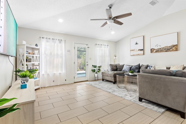 living room with ceiling fan, a textured ceiling, and vaulted ceiling