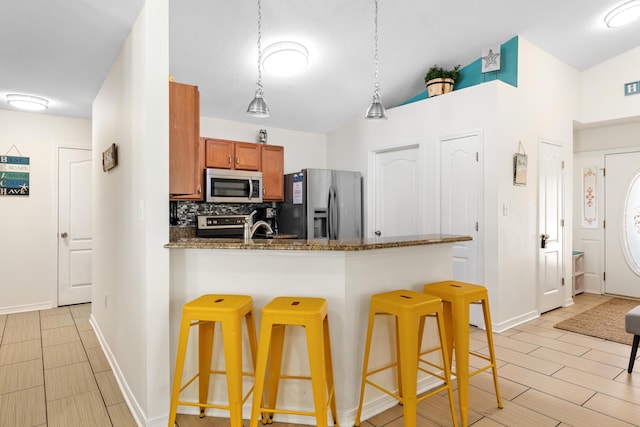 kitchen featuring stainless steel appliances, a kitchen breakfast bar, kitchen peninsula, pendant lighting, and decorative backsplash