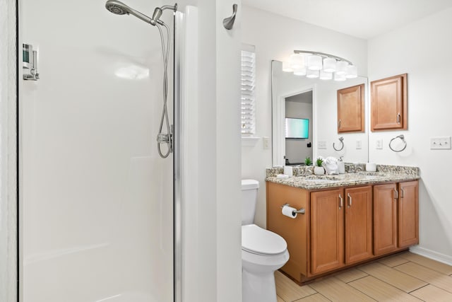 bathroom with vanity, a shower with shower door, and toilet