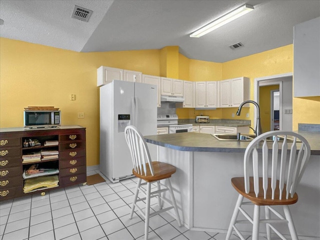 kitchen featuring white cabinetry, sink, white appliances, a breakfast bar, and light tile patterned floors