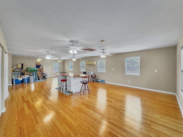 unfurnished living room with plenty of natural light, light wood-type flooring, and an AC wall unit