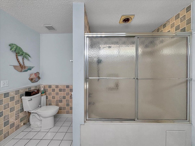 bathroom featuring tile patterned floors, toilet, and tile walls