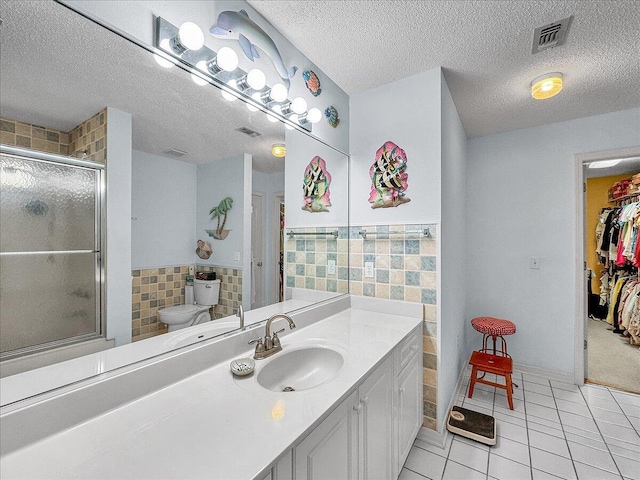 bathroom featuring tile patterned flooring, a shower with door, tile walls, and toilet