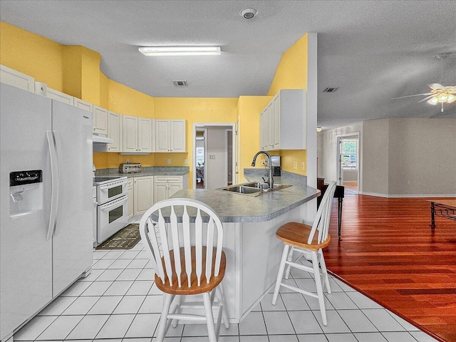 kitchen featuring white cabinetry, sink, a kitchen breakfast bar, white appliances, and light tile patterned floors