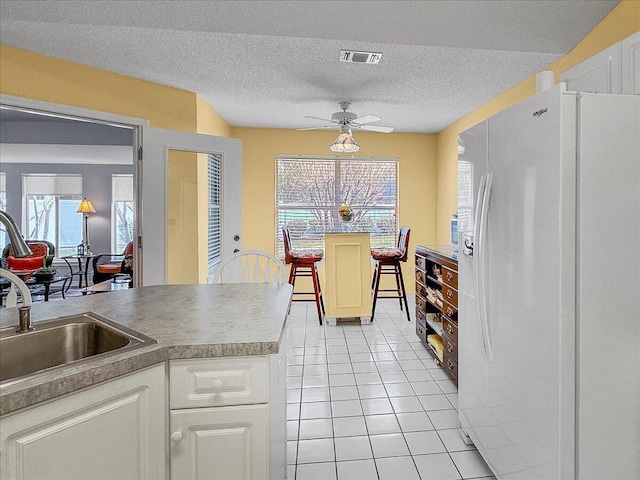 kitchen with white cabinets, ceiling fan, a healthy amount of sunlight, and white fridge with ice dispenser