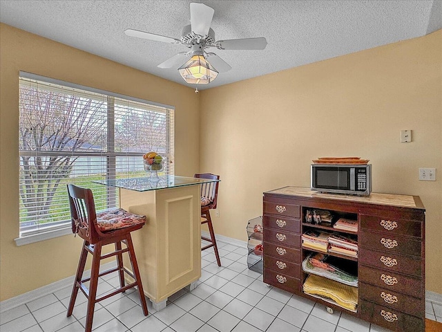 home office featuring light tile patterned floors, a textured ceiling, a wealth of natural light, and ceiling fan