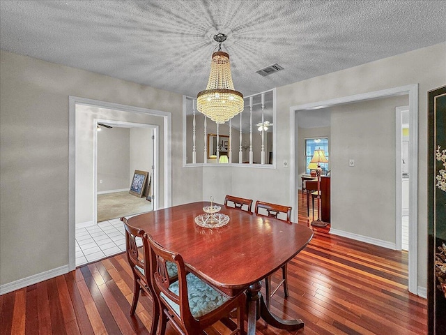 dining space with a notable chandelier, wood-type flooring, and a textured ceiling