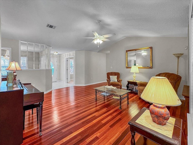 living room featuring vaulted ceiling, ceiling fan, a textured ceiling, and hardwood / wood-style flooring