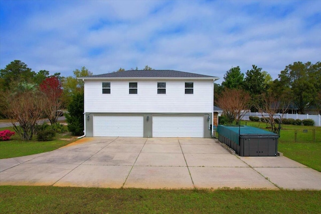 exterior space with a garage, a yard, and a hot tub