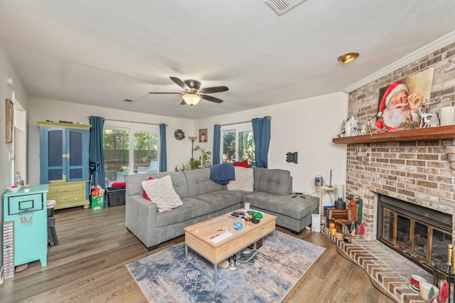 living room with ceiling fan, a brick fireplace, and hardwood / wood-style floors