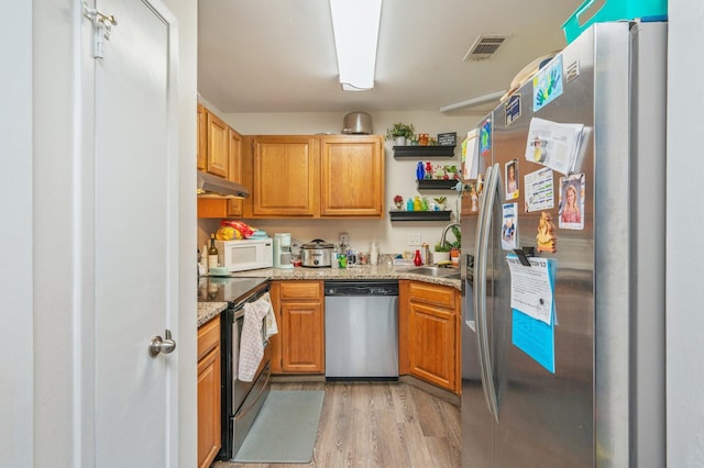 kitchen with sink, light stone counters, stainless steel appliances, and light hardwood / wood-style flooring